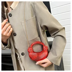 Détail du sac croissant rouge avec texture en spirale et bandoulière dorée