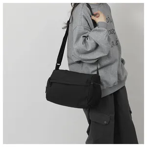 Vue latérale d'un sac bandoulière cylindrique noir en nylon sur un mannequin