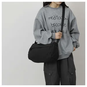 Détail du sac bandoulière en nylon noir avec sangle large réglable et fermeture éclair