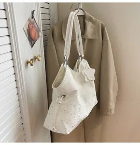 Détail du sac cabas crème avec imprimé étoiles, broderie et breloque étoile assortie