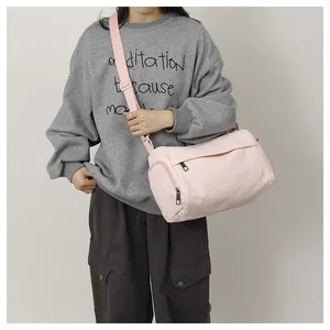 Détail d'un sac cylindrique en nylon rose clair avec bandoulière sur un mannequin femme