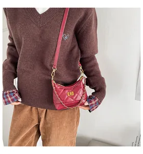 Détail du sac bandoulière matelassé rouge avec chaîne dorée et fermoir pivotant carré
