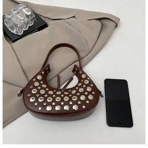 Detail view of a brown crescent bag with silver studs and a smooth leather finish
