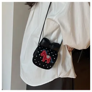 Détail du mini sac selle à pois blancs et broderie de cheval à bascule rouge sur le nœud
