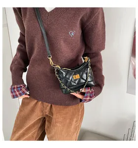 Détail du sac bandoulière en cuir matelassé noir avec fermoir doré et bandoulière chaîne