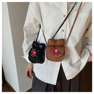 Détail du mini sac selle à pois avec décoration nœud et broderie cheval rouge