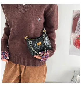 Détail d'un sac à bandoulière matelassé noir avec chaîne dorée et fermoir pivotant chic