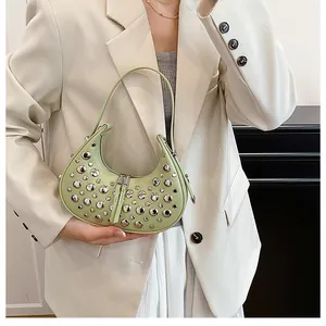 Detail of light green crescent bag with silver studs worn by a model in a beige suit