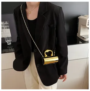Detail of a golden metallic cylinder bag with a sleek handle and fine chain strap