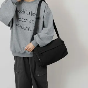 Sac tube en nylon noir minimaliste porté par un mannequin pour un style streetwear