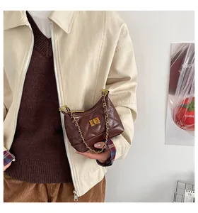 Détail du sac matelassé marron foncé avec poignée en chaîne dorée et fermoir rotatif