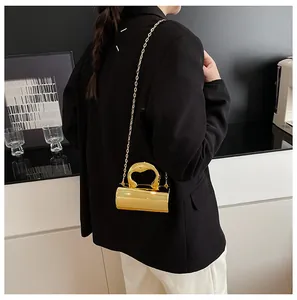 Close-up of golden cylinder evening bag with mirror finish and artistic metal handle
