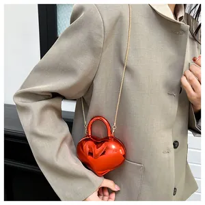 Detail of red heart-shaped mini crossbody bag with metallic finish and gold chain strap