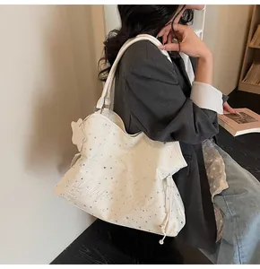 Détail d'un grand sac fourre-tout blanc cassé avec étoiles argentées et broderie