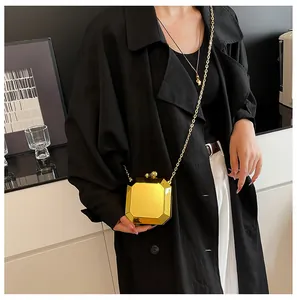 Fashionable model wearing a golden octagonal metal clutch bag with a sleek chain strap