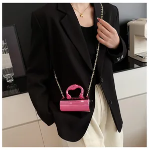 Detail of metallic pink mini cylinder bag with gold chain strap on black blazer