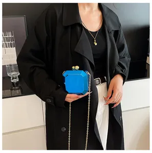 Detail of blue geometric clutch bag with gold chain strap and spherical metal clasp