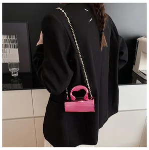Detail of a bright pink metallic cylinder bag with gold chain and irregular handle