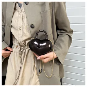 Close-up of black heart-shaped mirror bag with golden chain and curved handle