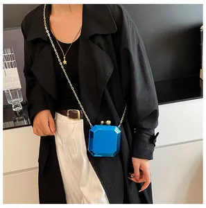Detail view of octagon gem-shaped blue bag with gold chain strap on model