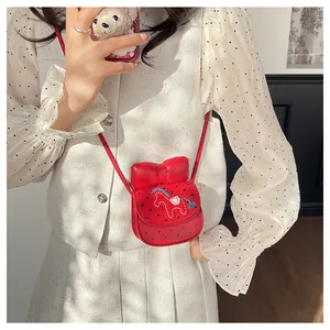 Gros plan d'un mini sac bandoulière rouge avec pois noirs et détail de broderie de poney