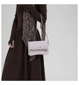 Detail view of pink crossbody bag with silver studs and chain strap on a vintage outfit