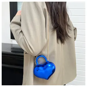 Macro view of blue heart shaped mini bag with mirror finish and gold chain strap