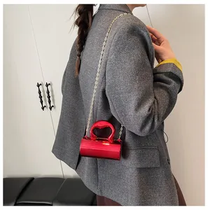 Detail of red cylinder mini bag with heart handle and gold chain on a model