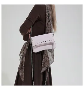 Detailed view of pink crossbody bag with silver studs and chain strap on a model