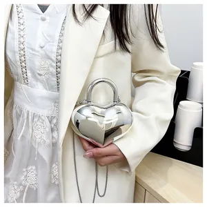 Detail of silver heart-shaped mirror bag with round handle and metal chain strap
