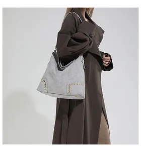 Close-up of a large grey hobo bag with gold stud rivets and smooth matte finish texture