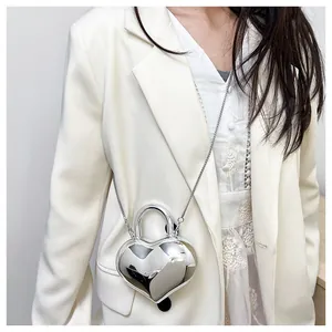 Close-up of heart-shaped silver mirror handbag with chain strap on a white suit jacket