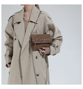 Macro shot of brown retro chain bag with silver studs and model wearing khaki trench coat