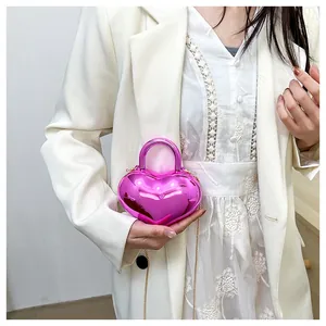 Detailed view of pink heart-shaped metallic crossbody bag with gold chain strap
