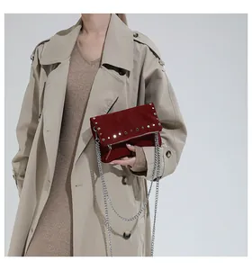 Macro detail of dark red suede handbag featuring silver rivets and metallic chain strap