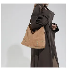 Detailed shot of retro brown suede tote with gold square studs on a shoulder strap
