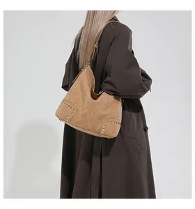 Detail of vintage brown suede hobo bag featuring gold rivet studs and leather shoulder strap