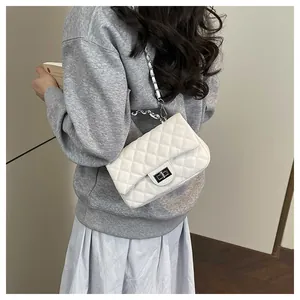 Close-up of white quilted chain bag featuring silver turn-lock and leather woven strap