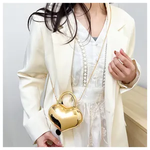 Macro shot of heart-shaped gold metallic handbag with mirror finish and gold chain strap