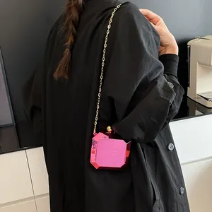 Chic pink gem-shaped acrylic crossbody bag with gold chain strap shown on model