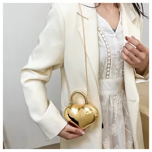 Macro view of a gold heart-shaped chain bag with metallic mirror finish and top handle