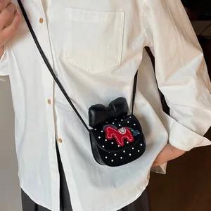 Mini sacoche à pois noirs avec nœud et broderie cheval sur une chemise blanche