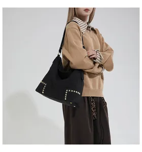 Detail of black suede tote bag featuring parallel gold studs and large capacity