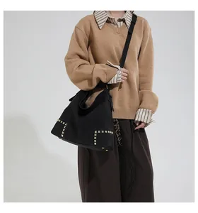 Detail of vintage black hobo bag featuring decorative gold square studs on shoulder strap
