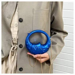 Detail of blue crescent moon bag with metallic mirror finish and golden chain strap