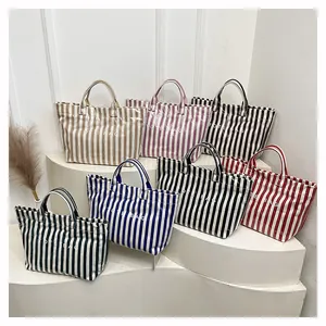 Détail de sacs cabas à rayures multicolores avec logo blanc sur fond minimaliste