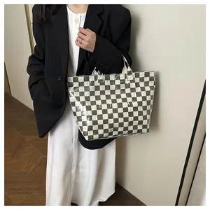 Close-up of a large checkered tote bag in dark green and cream with glossy finish