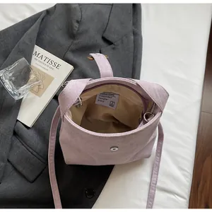 Detail of light purple suede shoulder bag with magnetic snap and brand label inside