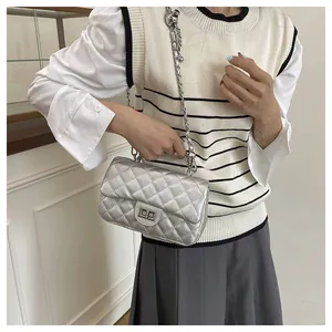 Close-up of silver quilted crossbody bag with metal chain strap and twist-lock on a model