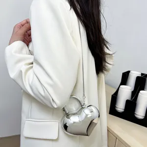Silver mirror heart-shaped chain crossbody bag shown with a white suit for a chic look
